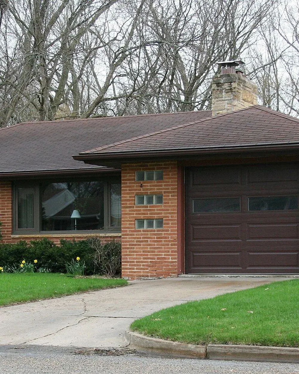 A brick mid-century home set back from the street on a wide lot in Country Club Manor, west Rochester.