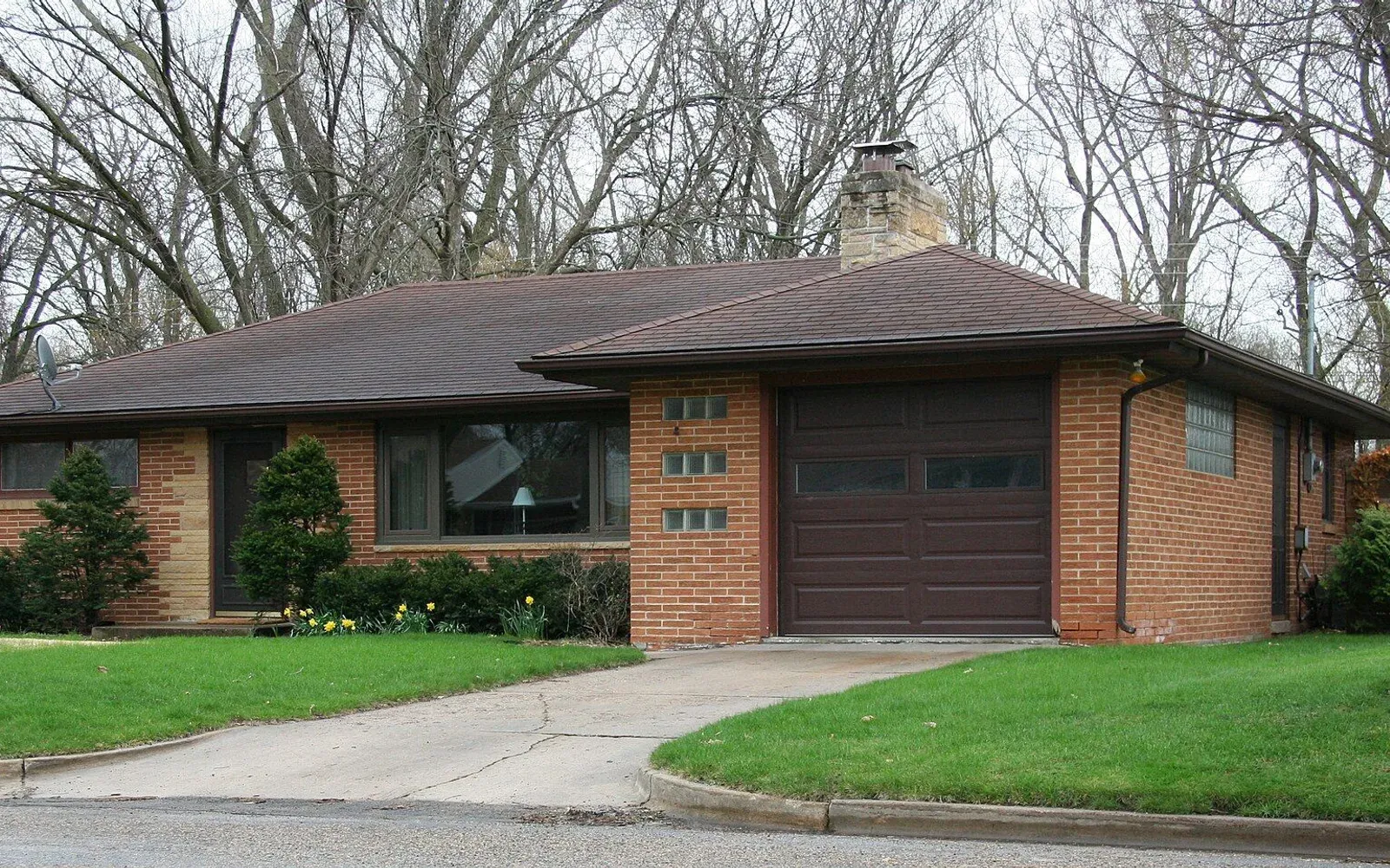 A brick mid-century home set back from the street on a wide lot in Country Club Manor, west Rochester.