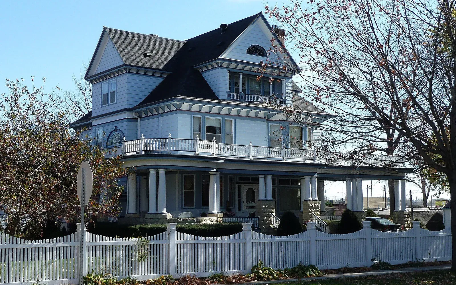 The Leuthold House, a Queen Anne Victorian home with a wraparound porch and white picket fence on a tree-lined street in Kasson, Minnesota.