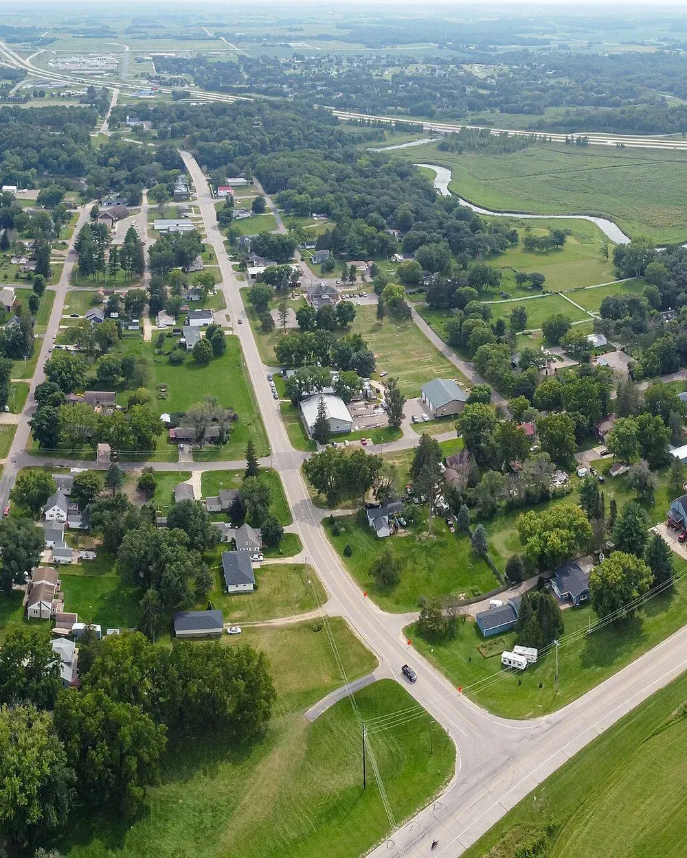 An aerial view of Oronoco, Minnesota, with tree-lined residential streets running toward Lake Zumbro in the distance.