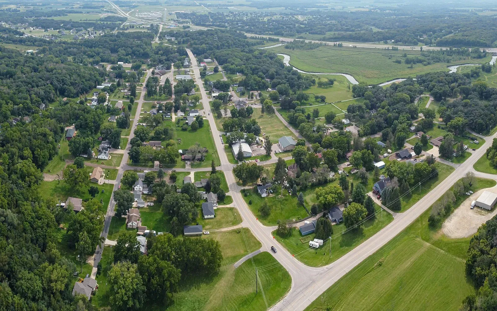 An aerial view of Oronoco, Minnesota, with tree-lined residential streets running toward Lake Zumbro in the distance.