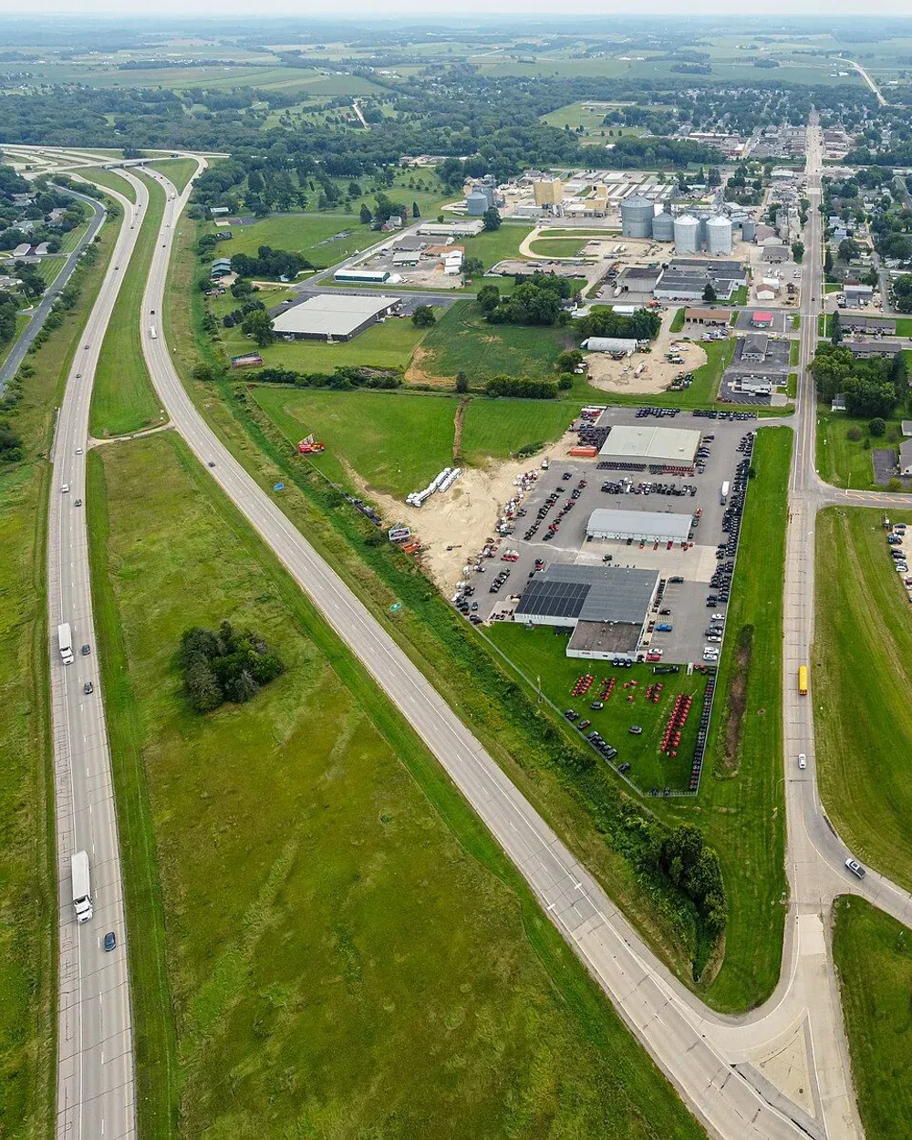 An aerial view of Pine Island, Minnesota, looking down the highway corridor toward town with farmland and commercial buildings flanking the road.