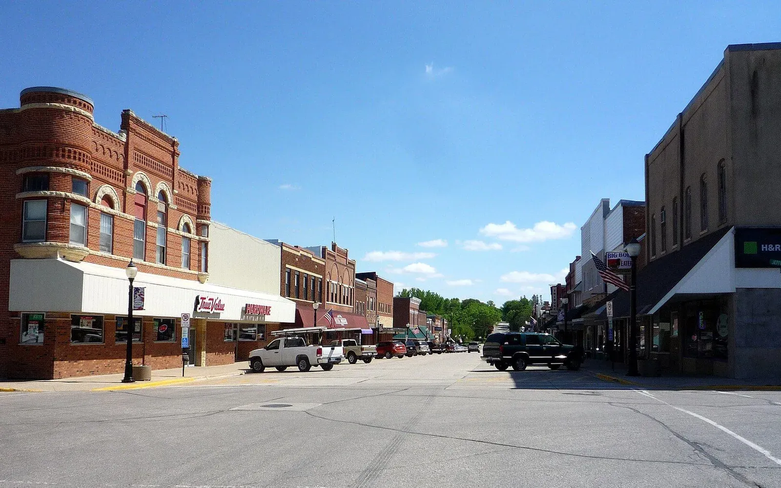 A view down a downtown street in Spring Valley, Minnesota, with historic brick storefronts under a summer sky.