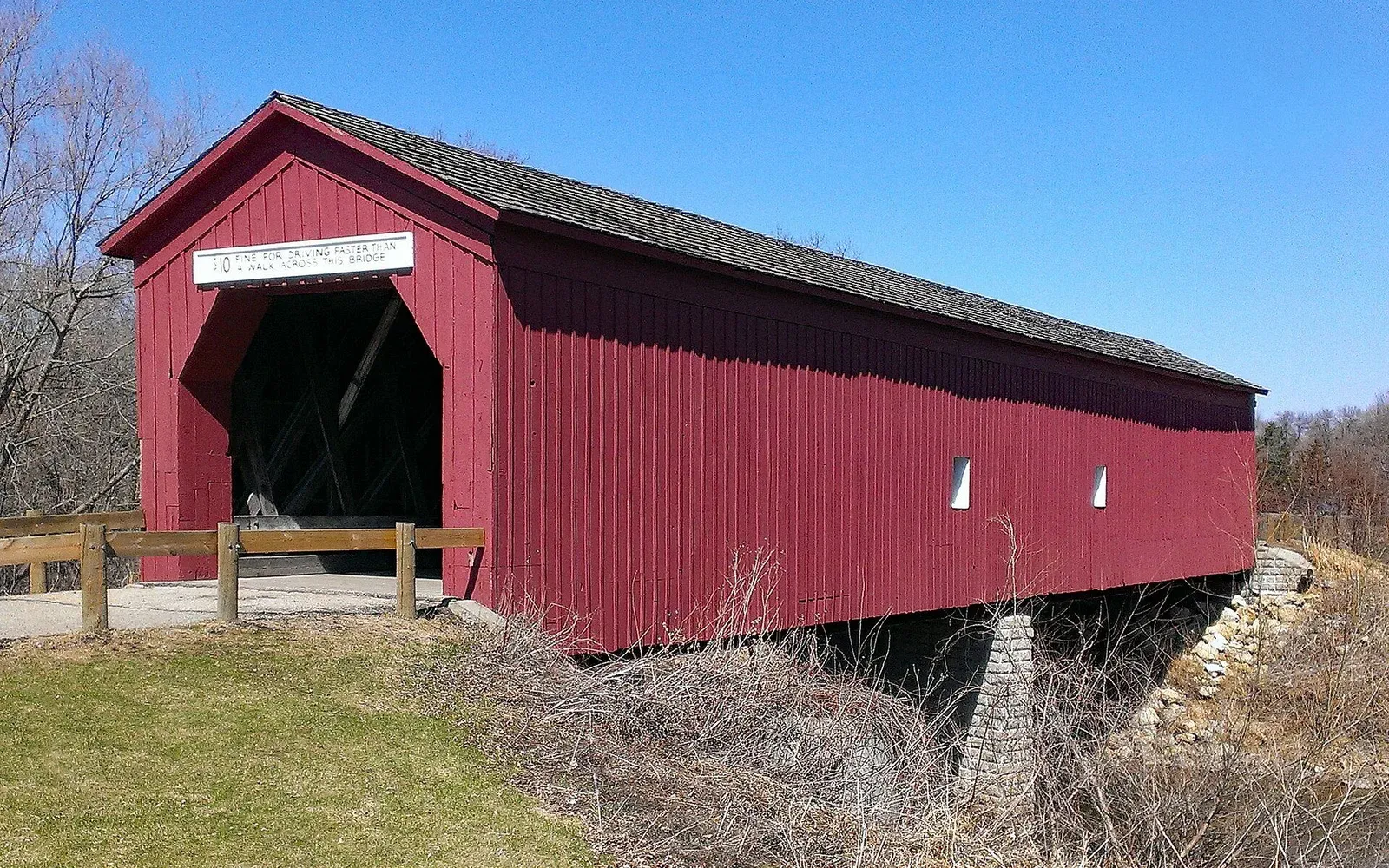 The Zumbrota covered bridge, the last historic covered bridge in Minnesota, seen across a snowy Covered Bridge Park in winter.